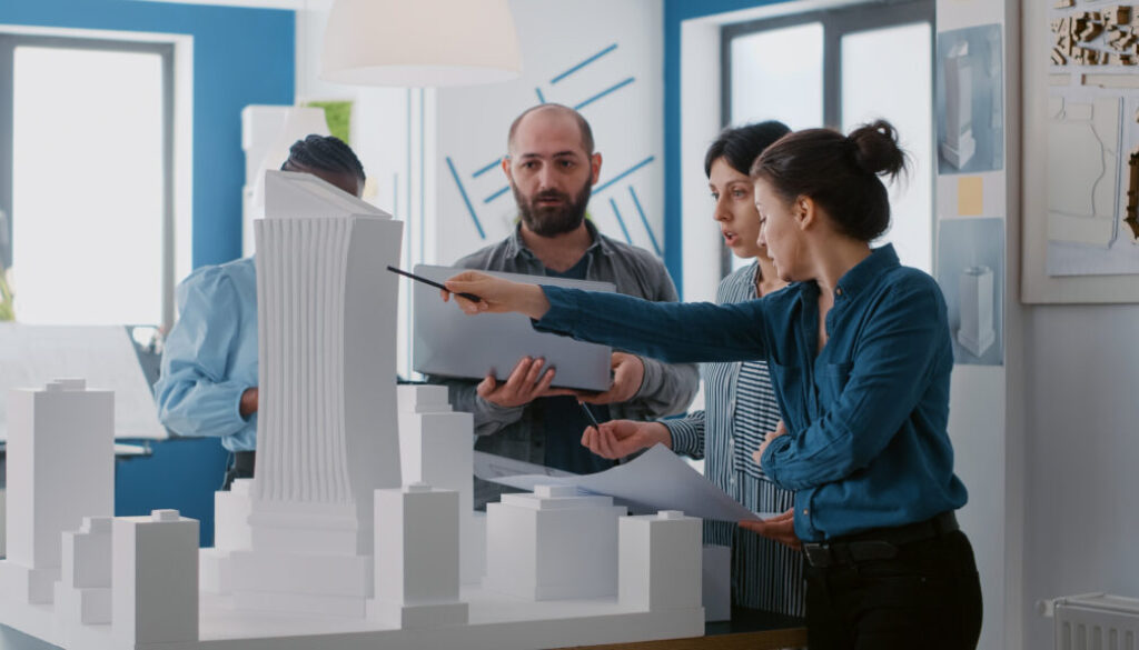 Multi ethnic people working with laptop, tablet and building model for architecture project