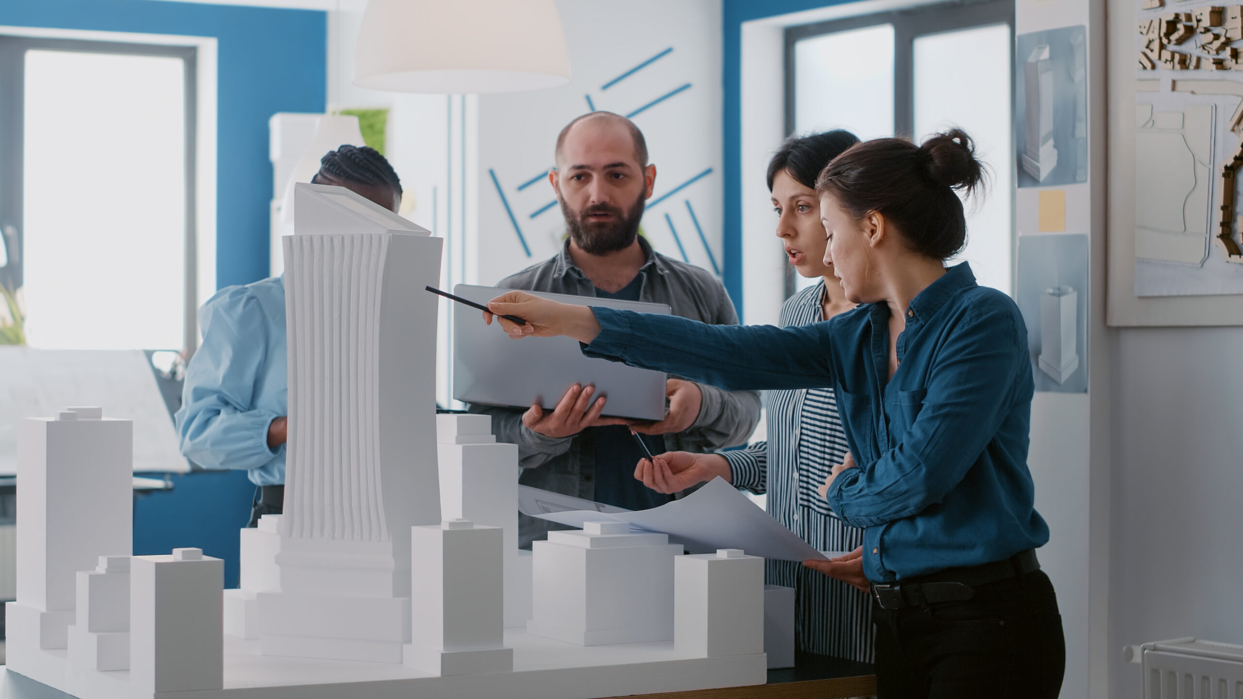 Multi ethnic people working with laptop, tablet and building model for architecture project